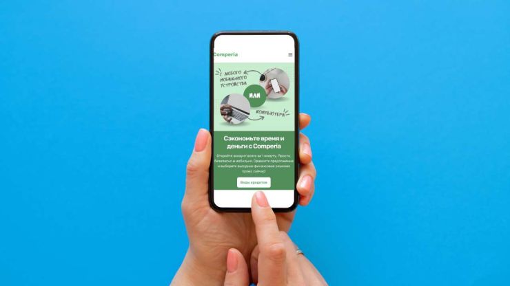 В женской руке телефон с открытым сайтом Comperia, на котором можно найти выгодные потребительские кредиты