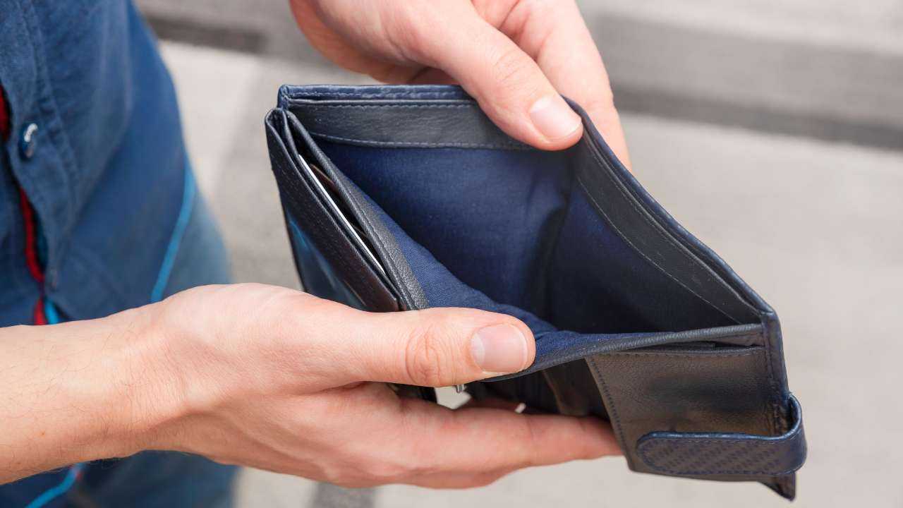 Человек в руках держит пустой кошелек, задаваясь вопросом «почему всегда не хватает денег»