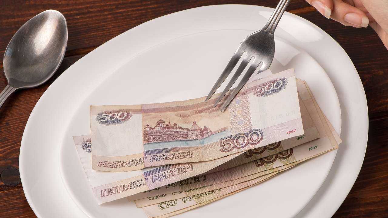 На тарелке лежат банкноты номиналом 500 рублей, рядом столовая ложка и вилка – часть минимальной зарплаты в России