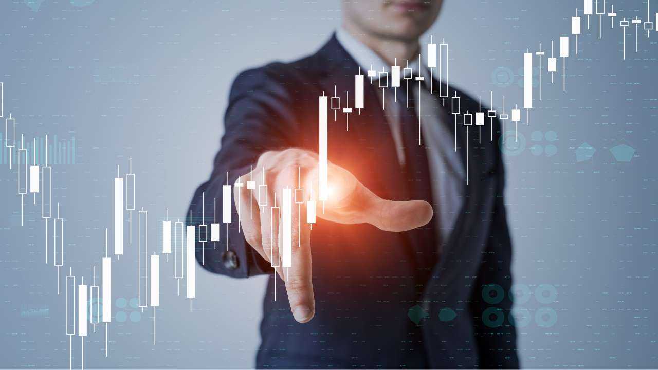 Мужчина в деловом костюме указывает на 3-d моделированные графики, символизирующие финансовые привычки