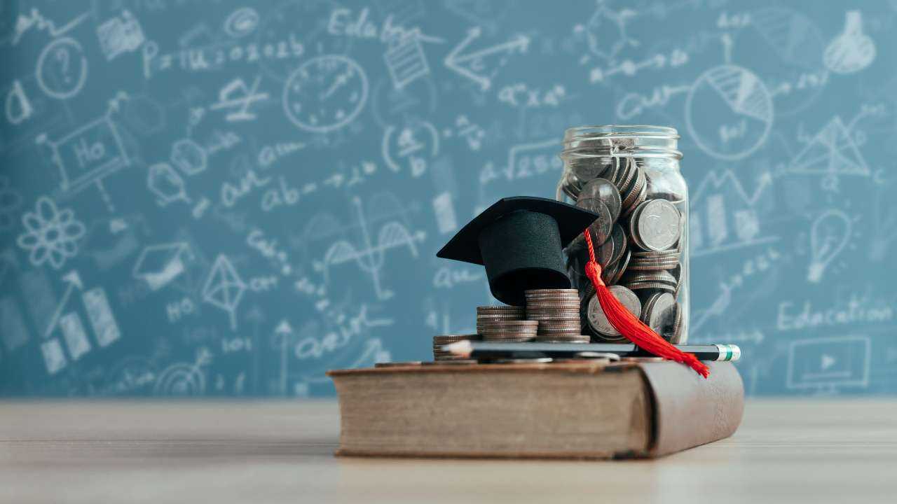 Книга, карандаш, шляпы выпускника, банка с монетами на фоне доски с формулами – финансовое воспитание начинается в детстве