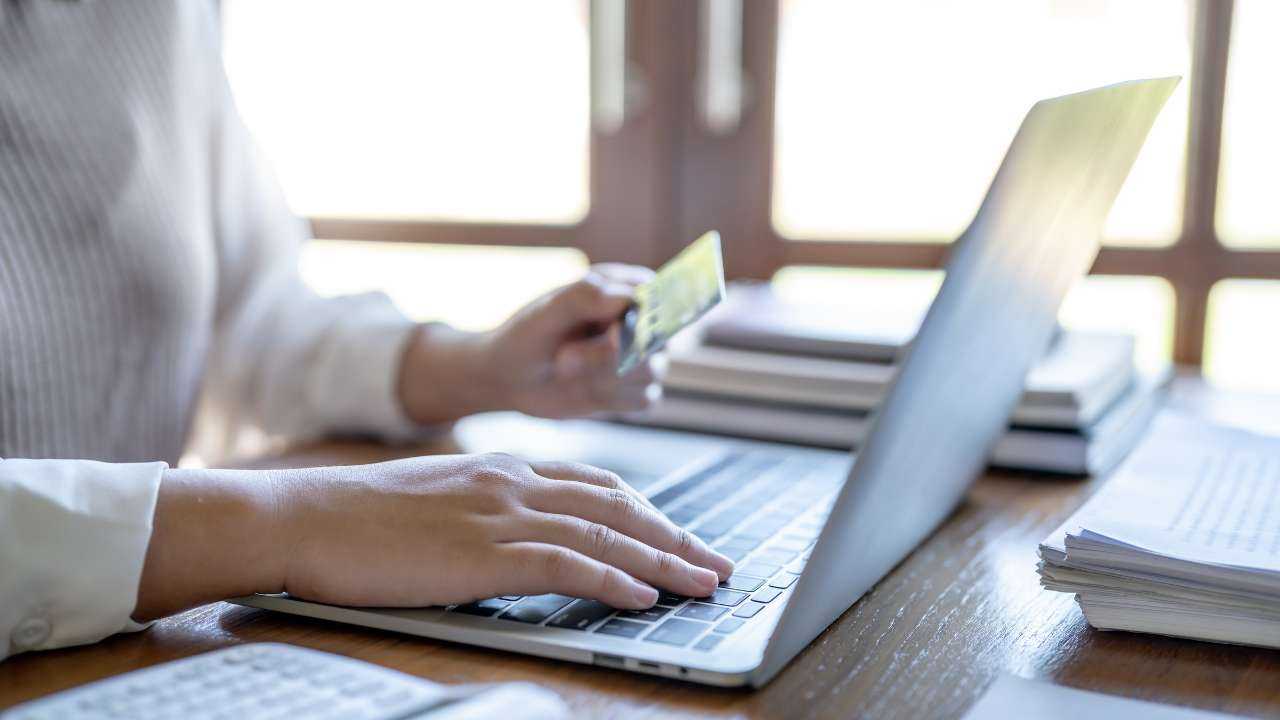Женщина использует ноутбук и банковскую карту для оформления кредитов и займов онлайн