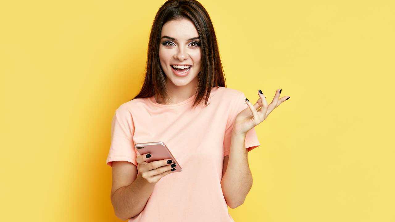 Девушка держит в руке смартфон, на котором нашла важную информацию о том, как выбрать и получить займ, и радостно улыбается